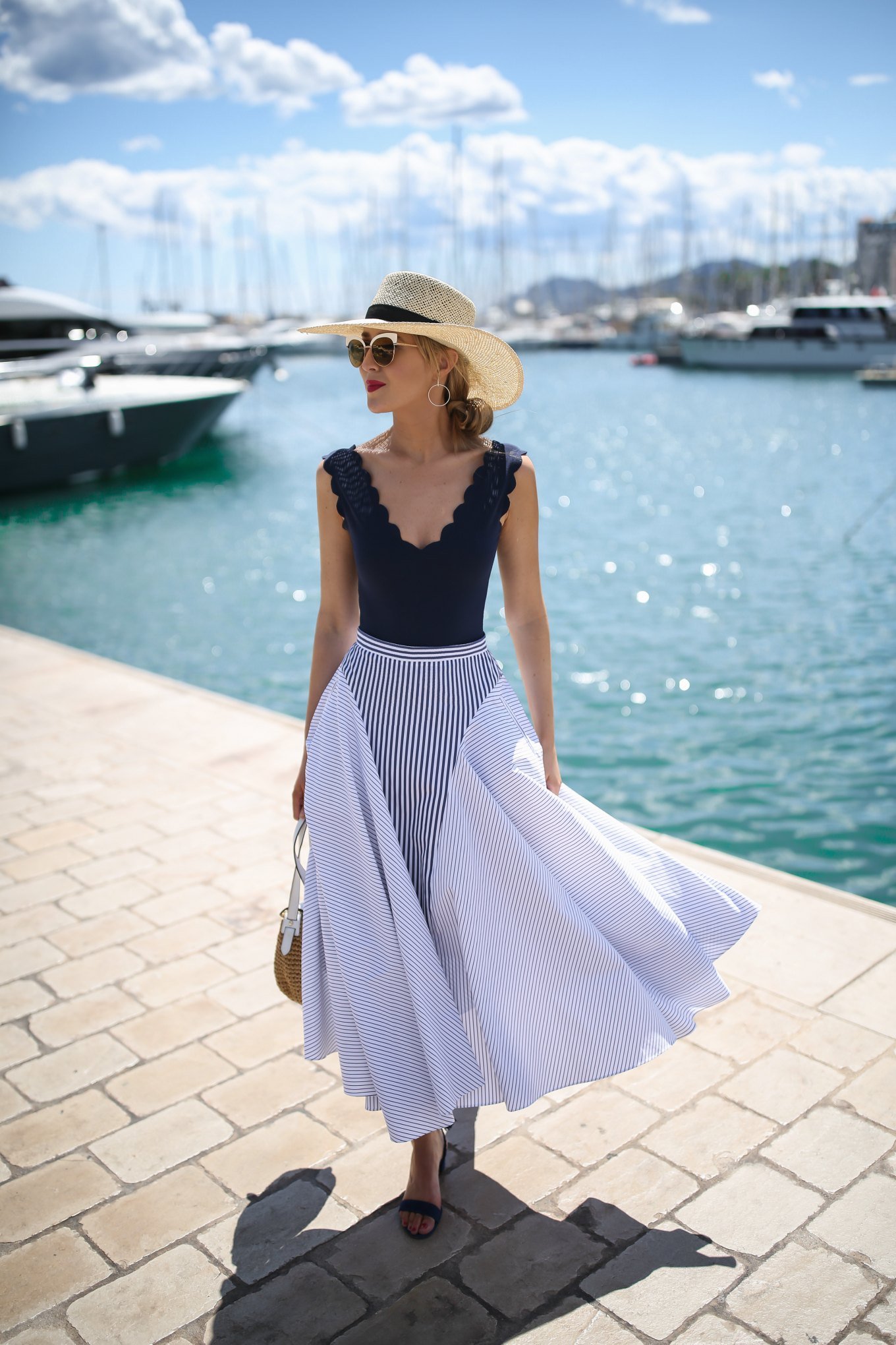 New York fashion blogger wearing a navy scalloped one piece bathing suit as a bodysuit with a blue pinstripe midi skirt black block heel sandals white metal sunglasses and a straw boater hat