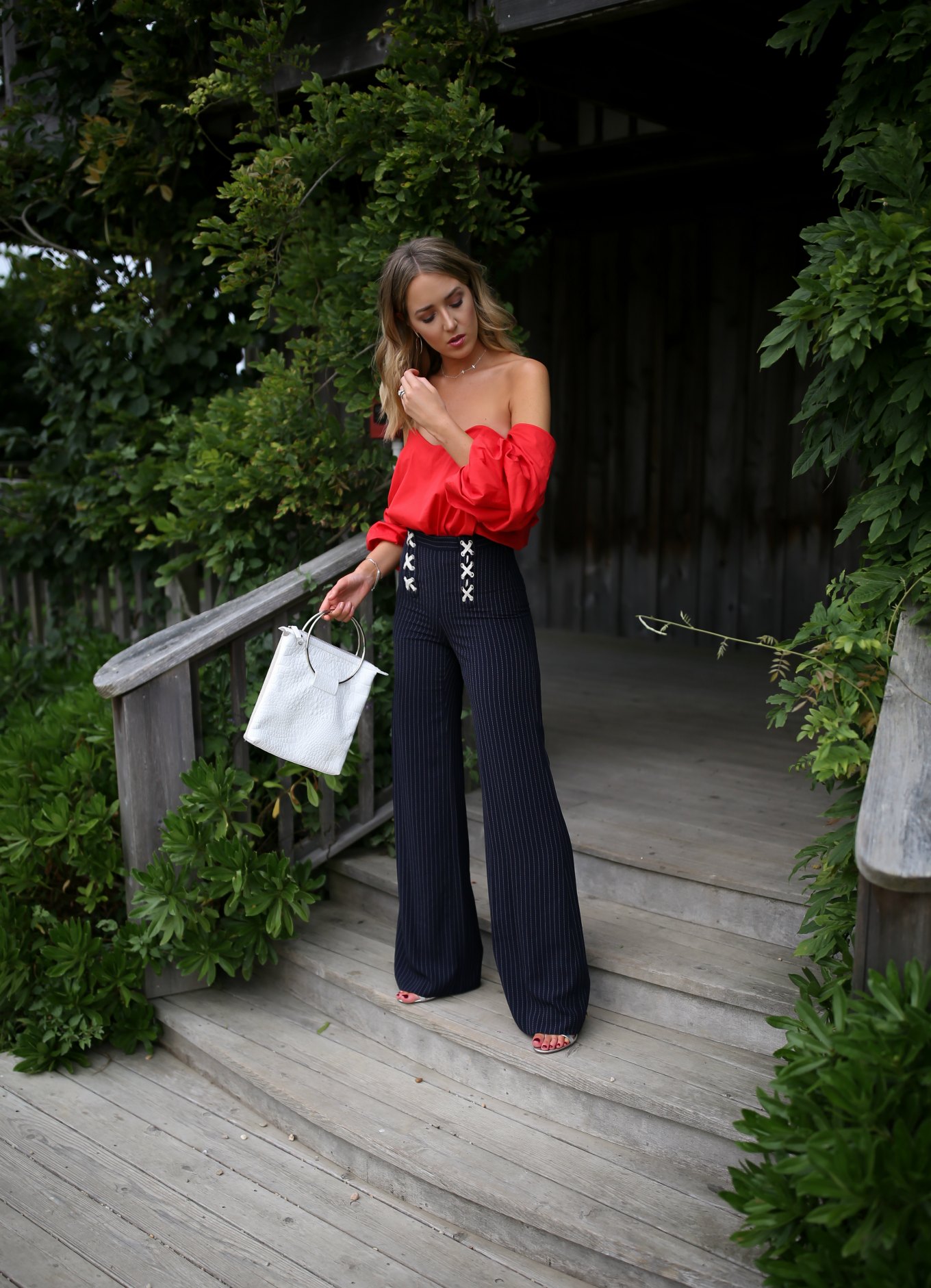 NYC fashion blogger Mary Orton in red Carolina Constas off the shoulder top and Veronica Beard x lace up pinstripe wide leg pants
