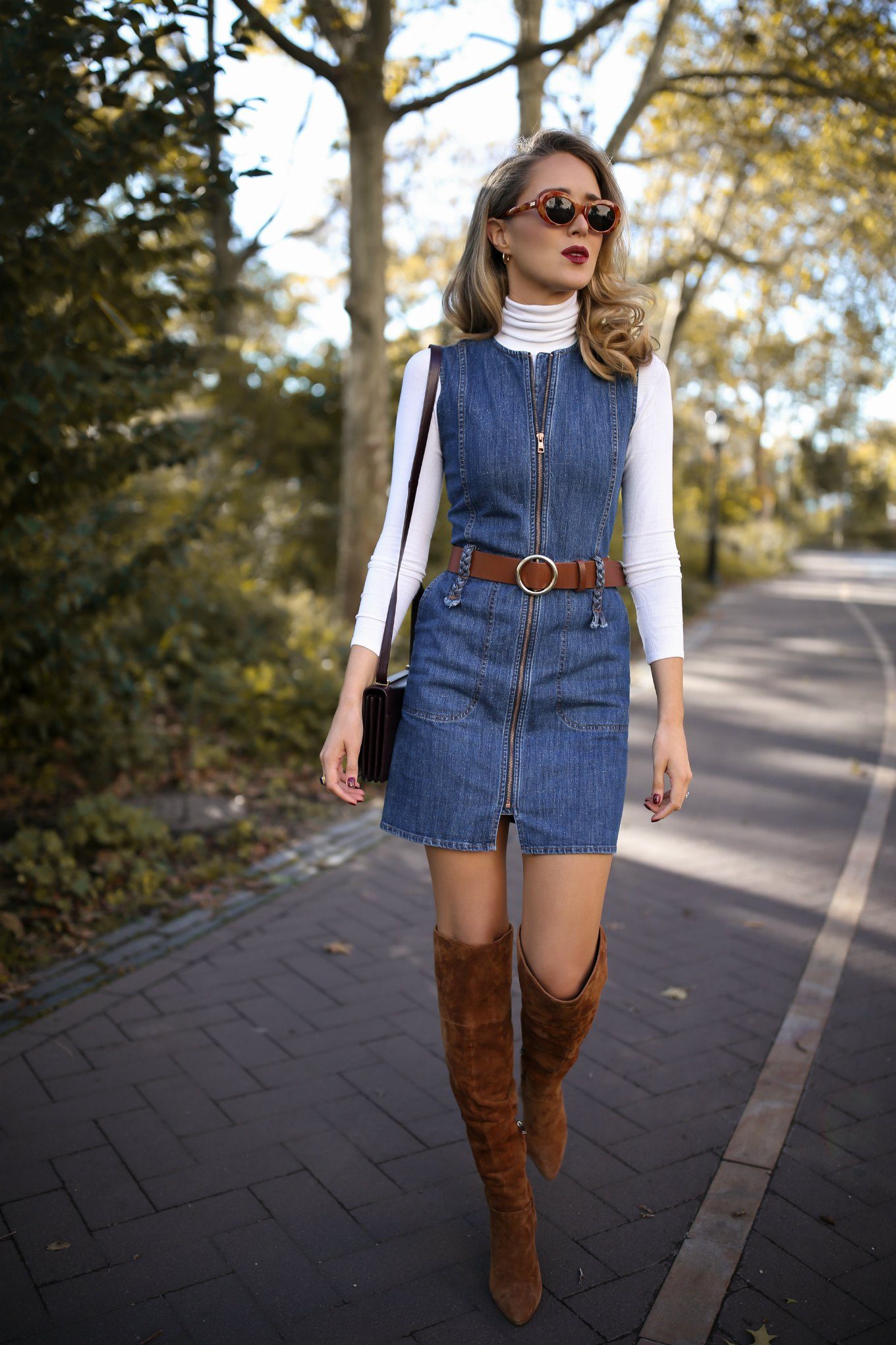 NYC fashion blogger Mary Orton of Memorandum wears a See by Chloe front-zip denim dress, a white layering turtleneck, a brown Frame leather belt, brown suede over-the-knee boots and a burgundy YSL bag