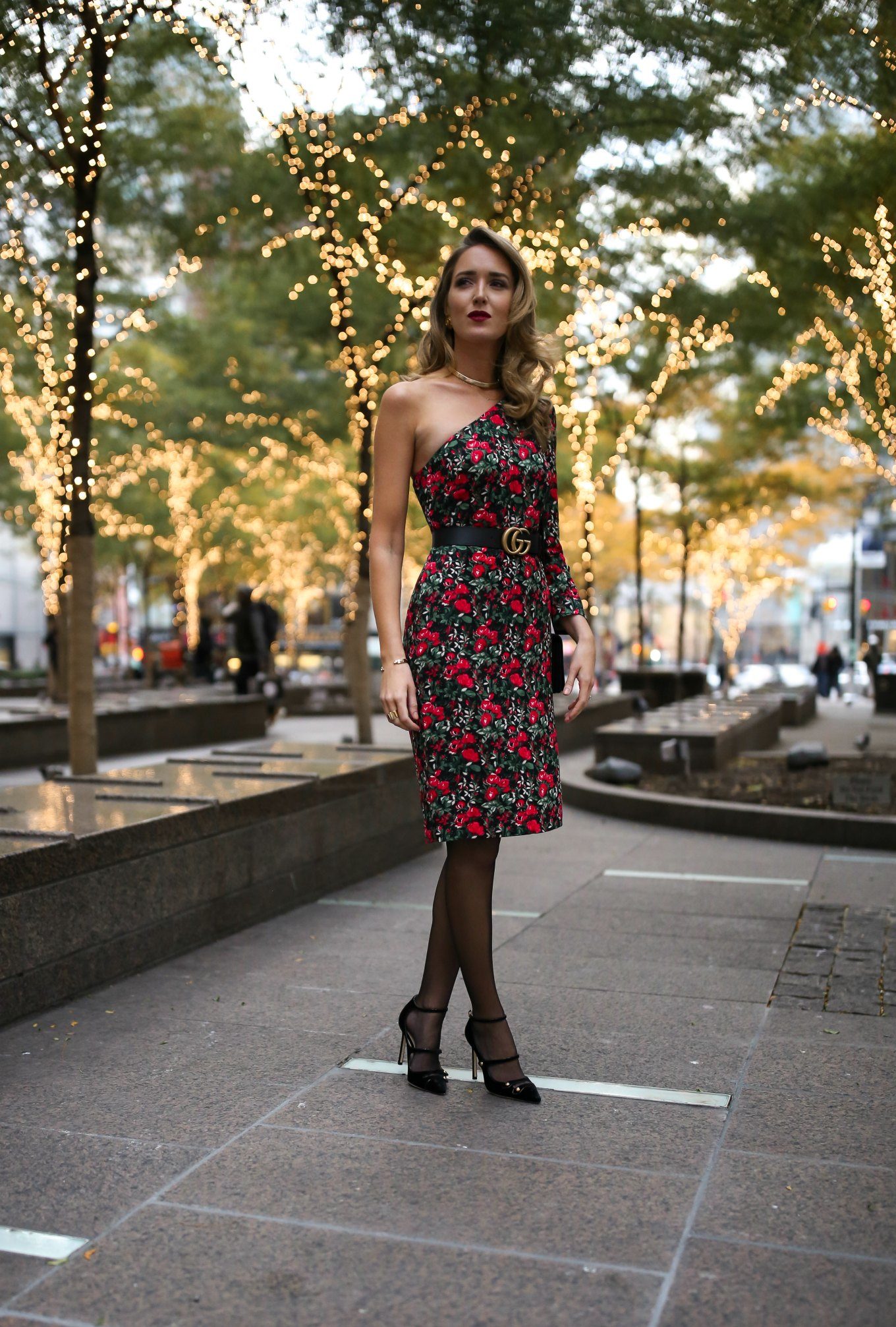NYC fashion blogger Mary Orton of Memorandum wears a Club Monaco red and green floral one-shoulder dress, a black leather Gucci waist belt, black strappy Mary Jane pumps and a deep red lip for Christmas