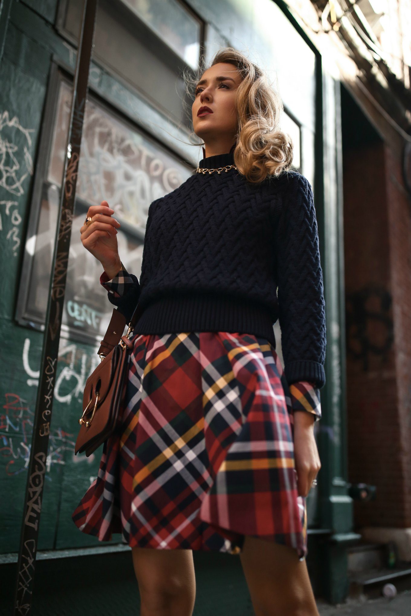NYC fashion blogger Mary Orton wears a Brooks Brothers red tartan plaid shirt dress with a navy cable knit sweater, a brown leather JW Anderson handbag and a gold statement necklace for a casual office holiday party