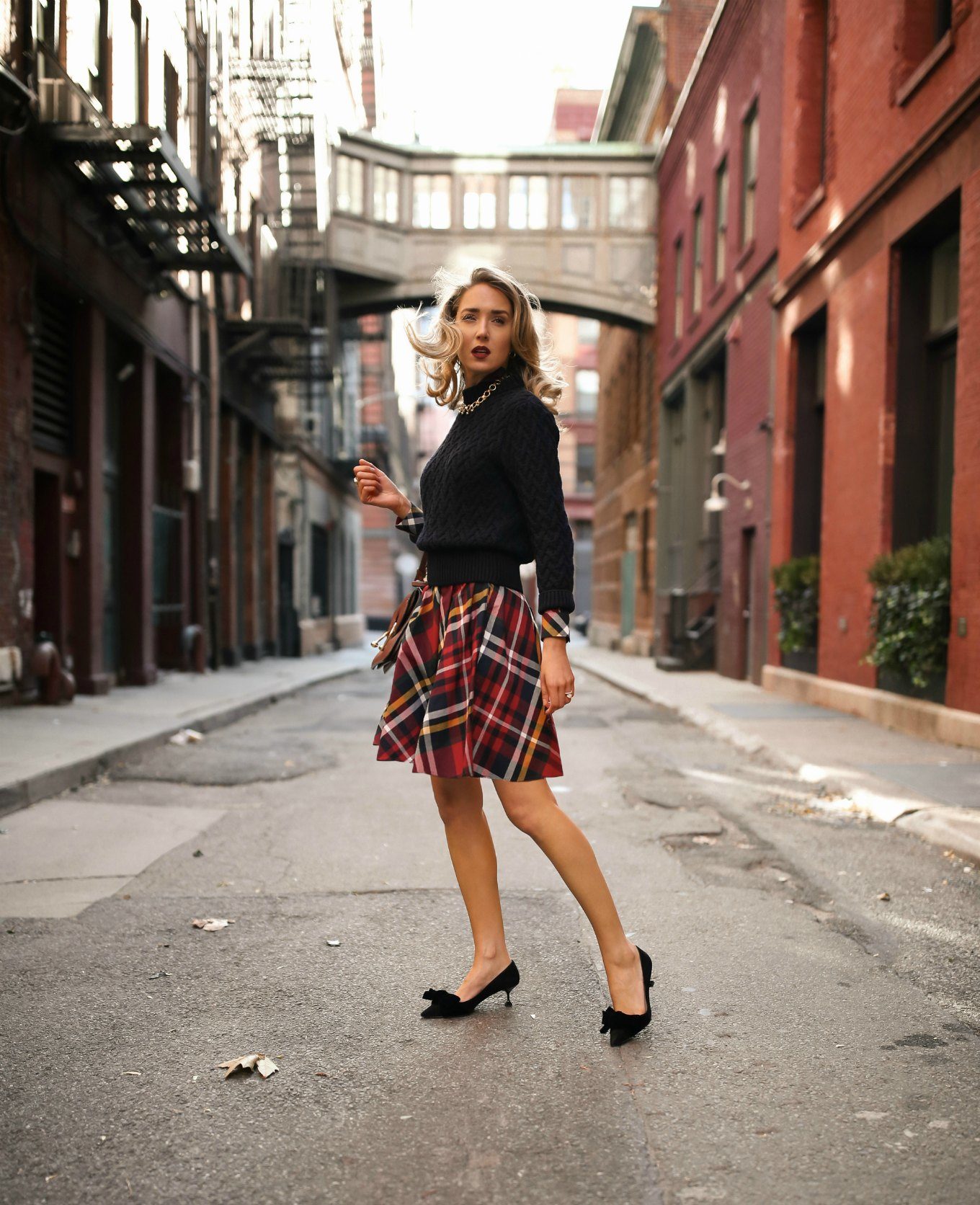 NYC fashion blogger Mary Orton of Memorandum wears a Brooks Brothers red tartan plaid shirt dress with a navy cable knit sweater, a brown leather JW Anderson handbag, black Miu Miu bow pumps and a gold statement necklace for a casual office holiday party