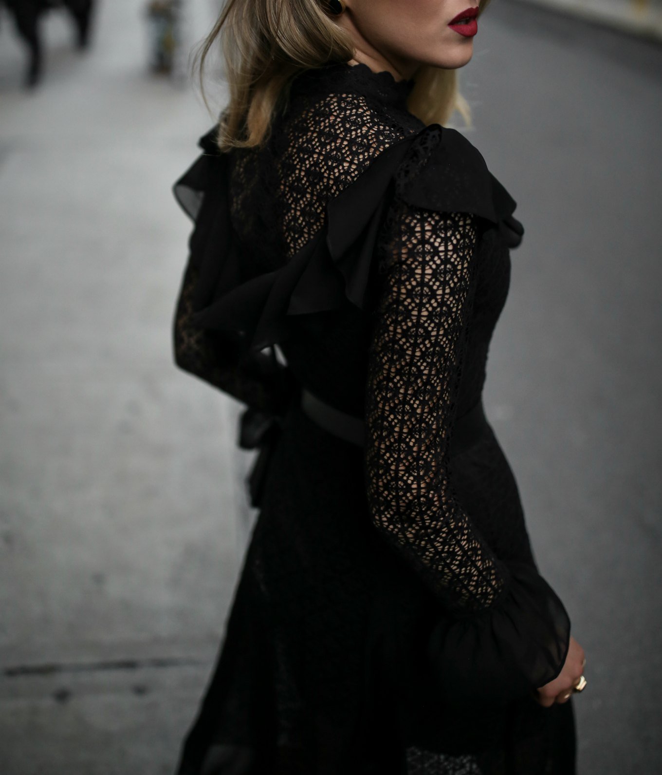 Mary Orton from Memorandum poses from the side wearing a black lace midi dress and a dark red lip