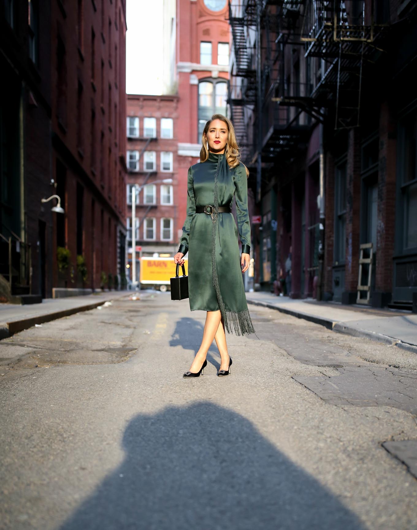 Mary Orton wearing emerald green Gabriela Hearst fringe detail midi dress, black chloe waist belt, black satin Manolo Blahnik Hangisi pumps, Victoria Beckham top handle box bag and dark red lip