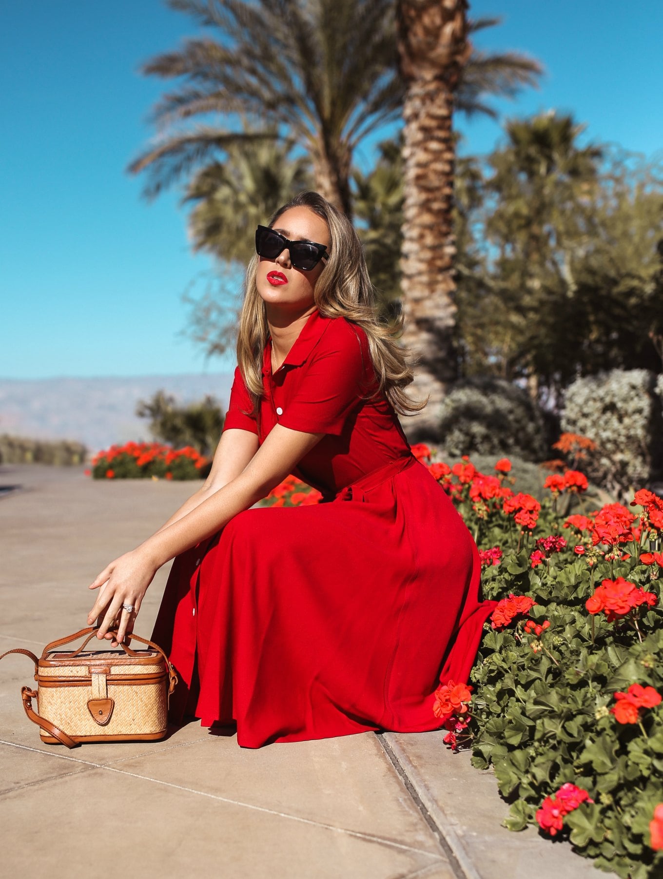 Fashion blogger wearing a red short sleeve shirt dress with a woven wicker box bag and black oversized cat eye sunglasses