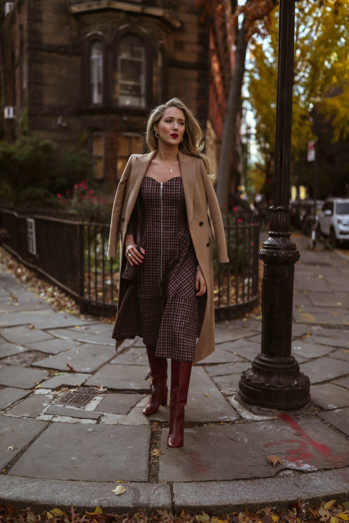 NYC style blogger in plaid dress, red boots and camel coat