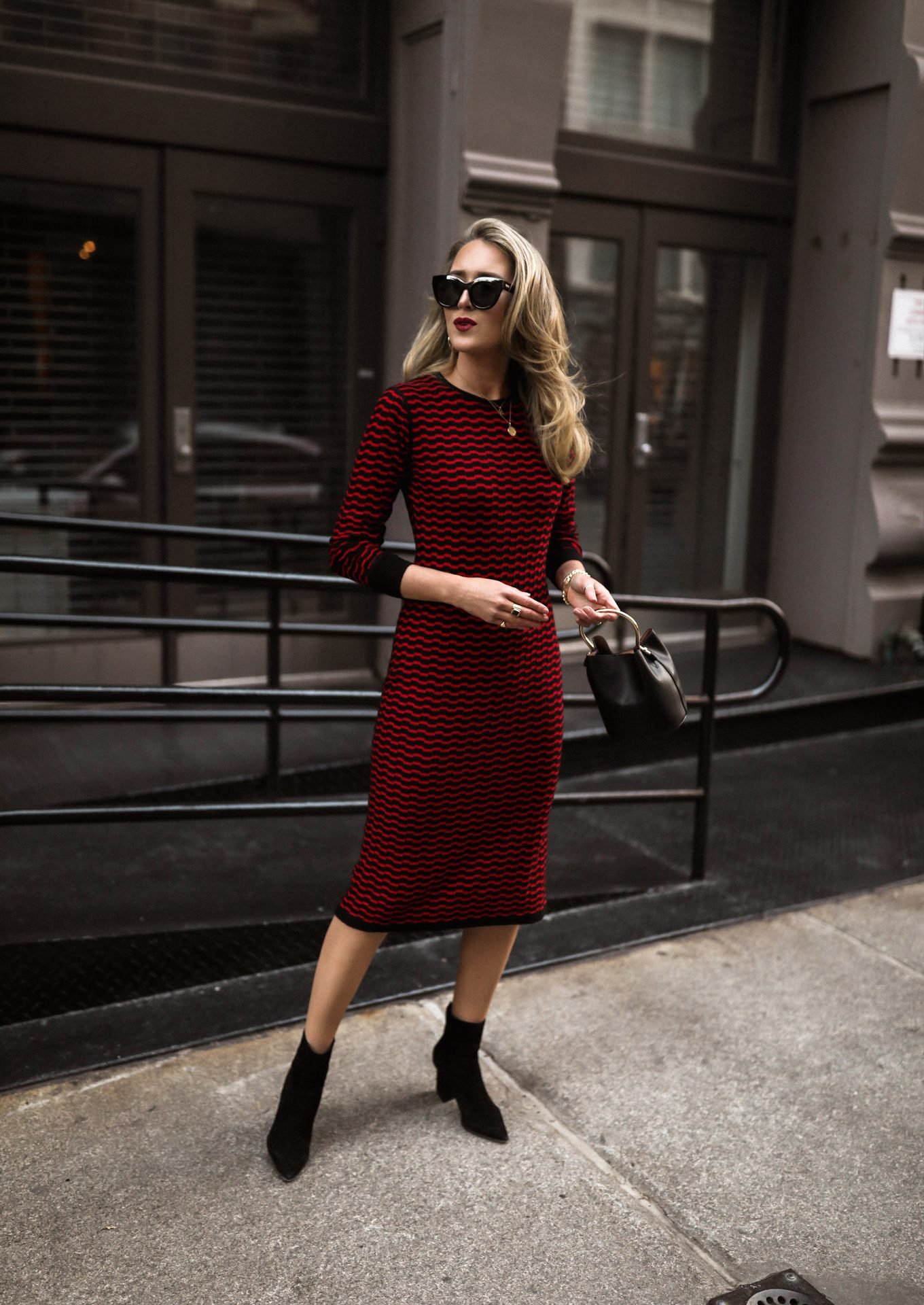 NYC style blogger in red knit textured dress with long sleeves, worn with black booties, bag, sunglasses and jewelry